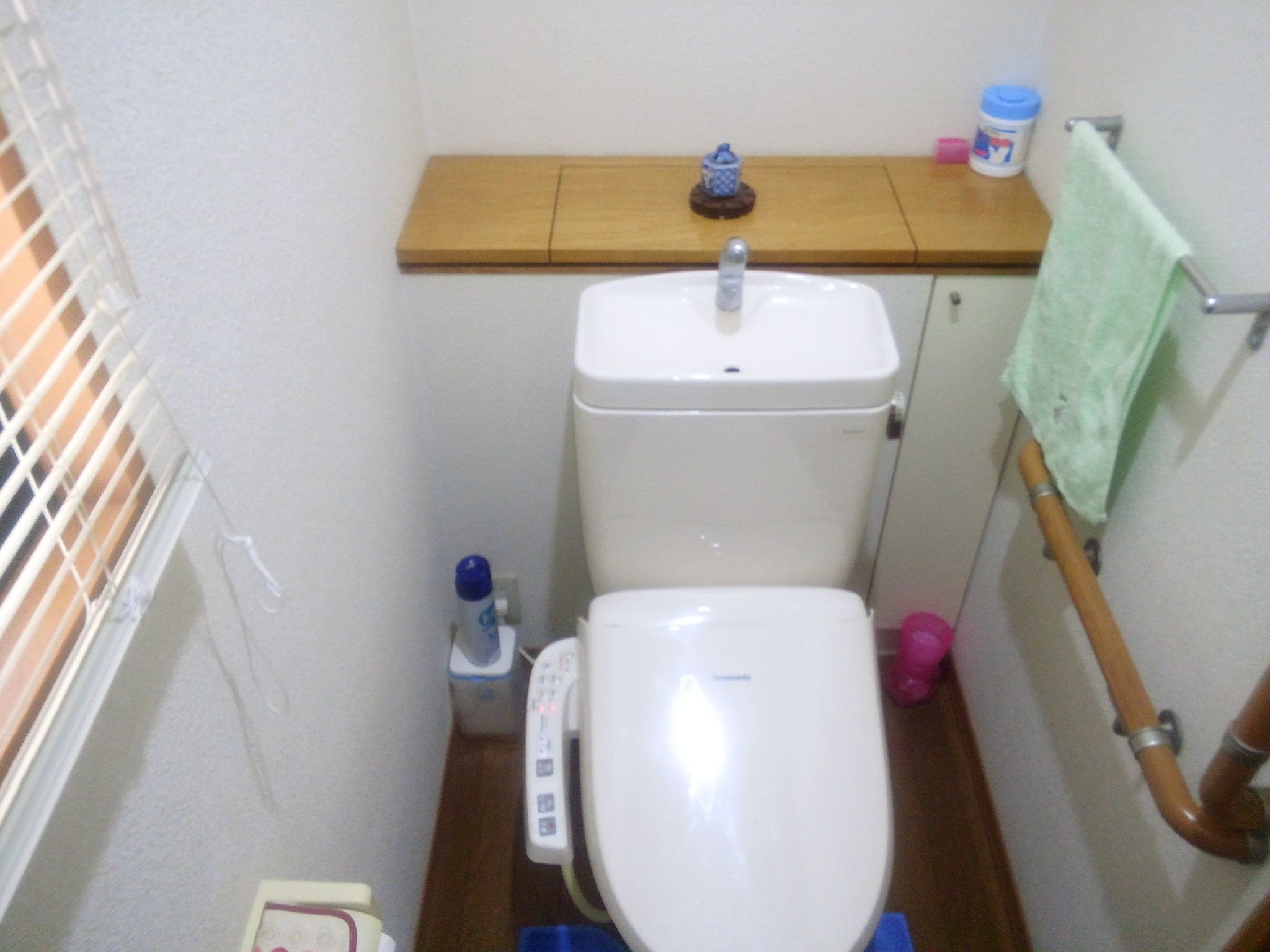 Ein kleines Badezimmer mit Toilette, Waschbecken und einem Holzregal darüber.