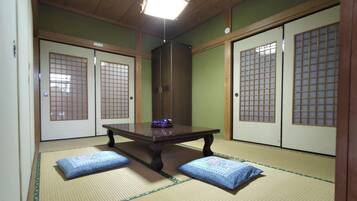 A traditional Japanese room with tatami flooring, a low table with cushions, and sliding doors with grid patterns.