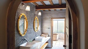 Un baño moderno con un espejo grande, dos lavamanos y un banco de madera.