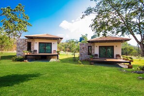 Two modern houses with stone walls and tiled roofs, surrounded by well-maintained lawns and trees. - Mela Garden Retreat Cottage (Muak Lek)