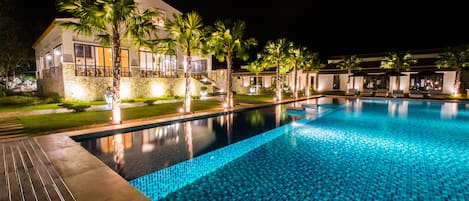Una piscina al aire libre, sombrillas, sillones reclinables de piscina
