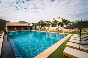 Alberca al aire libre, sombrillas en la alberca y camastros