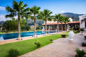 Una piscina al aire libre, sombrillas, sillones reclinables de piscina