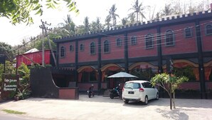 A building with a red brick facade, arched windows, and a sign indicating 'Cafe Johan Restaurant Homestay'. - Café Johan Home Stay Senggigi (Senggigi)