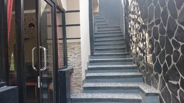 A staircase with stone steps leading to a room with a glass door and a red curtain. - Café Johan Home Stay Senggigi (Senggigi)