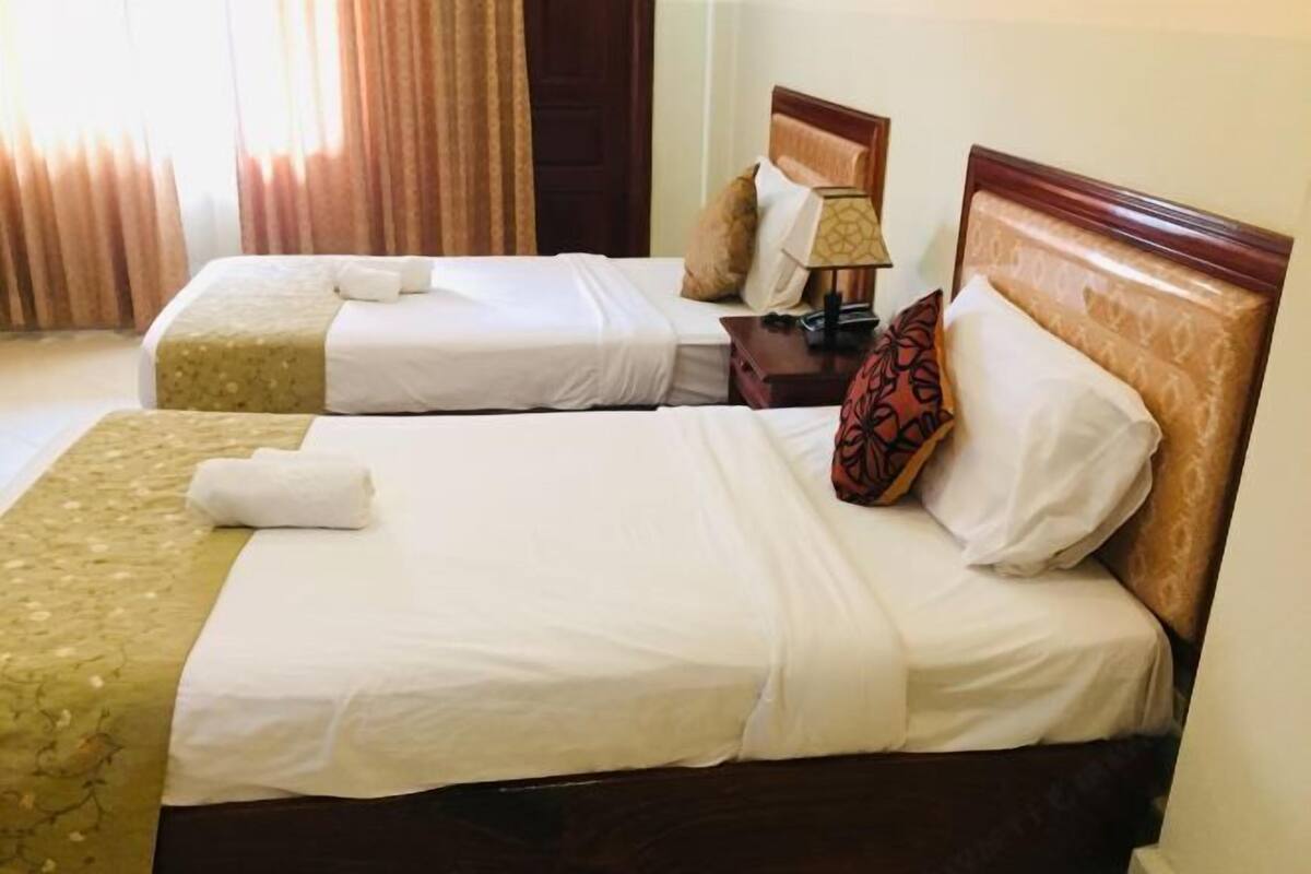 Ein Hotelzimmer mit zwei Betten, einem Nachttisch mit Lampe und einer Tür.