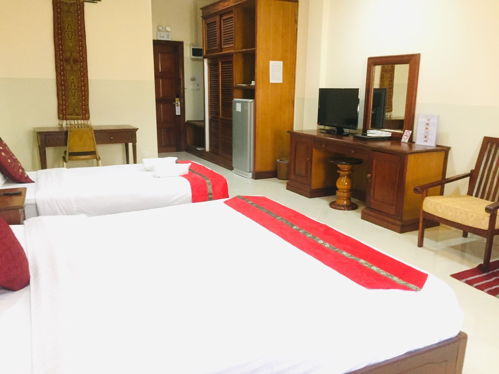 A hotel room with two beds, a television, a desk, a wardrobe, and a chair.