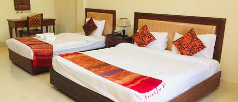 A hotel room with two single beds, a large bed, and a chair.