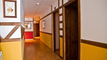 Un pasillo con suelo de madera, un cuadro enmarcado en la pared y una puerta con el símbolo del número.
