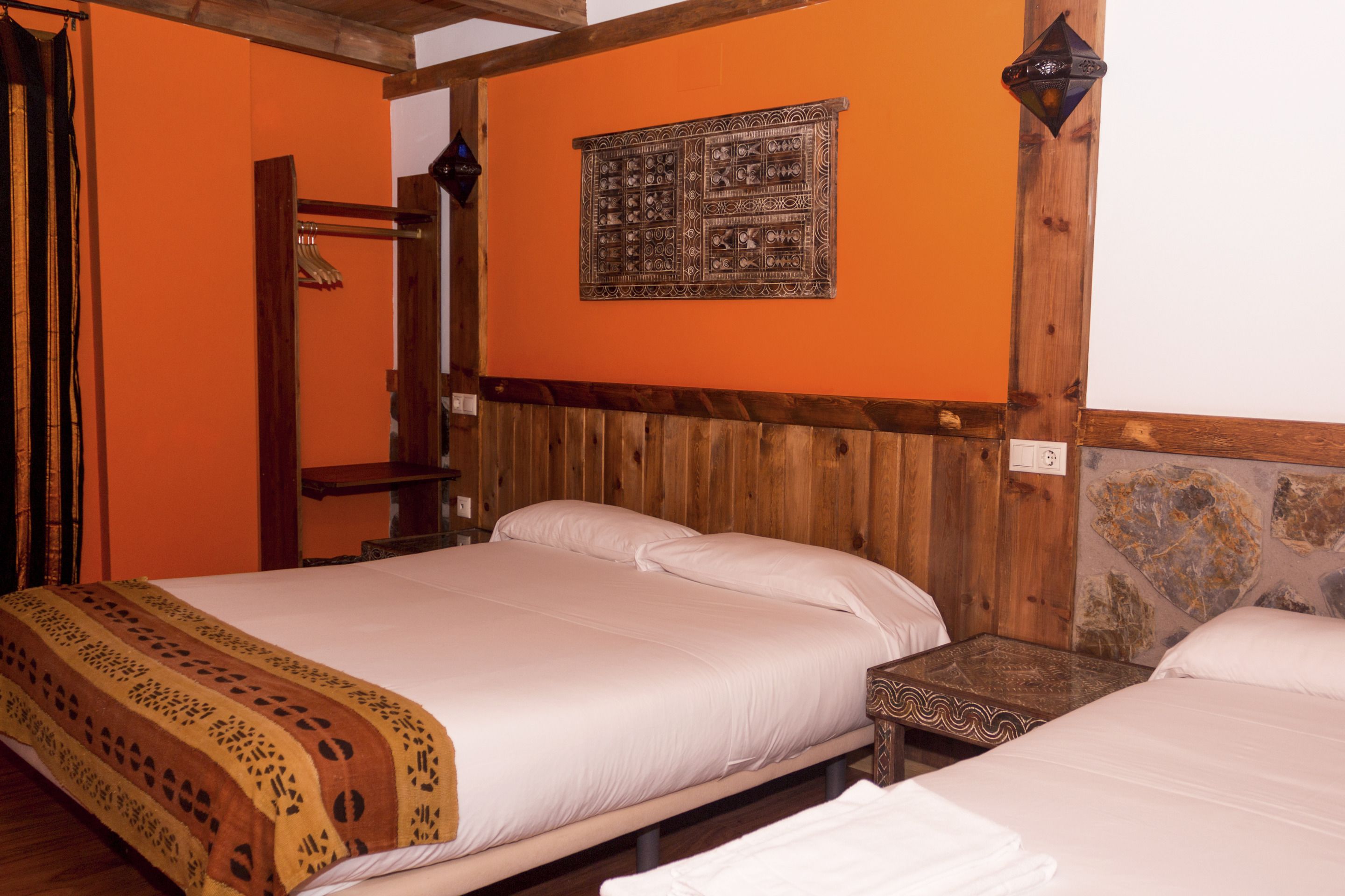 Una habitación con una cama de madera, una pared de piedra y un techo de madera.