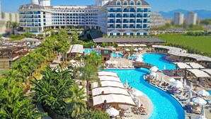 A large hotel with multiple floors, a swimming pool, and lush greenery. - Adalya Elite Lara Hotel - All Inclusive (Antalya)