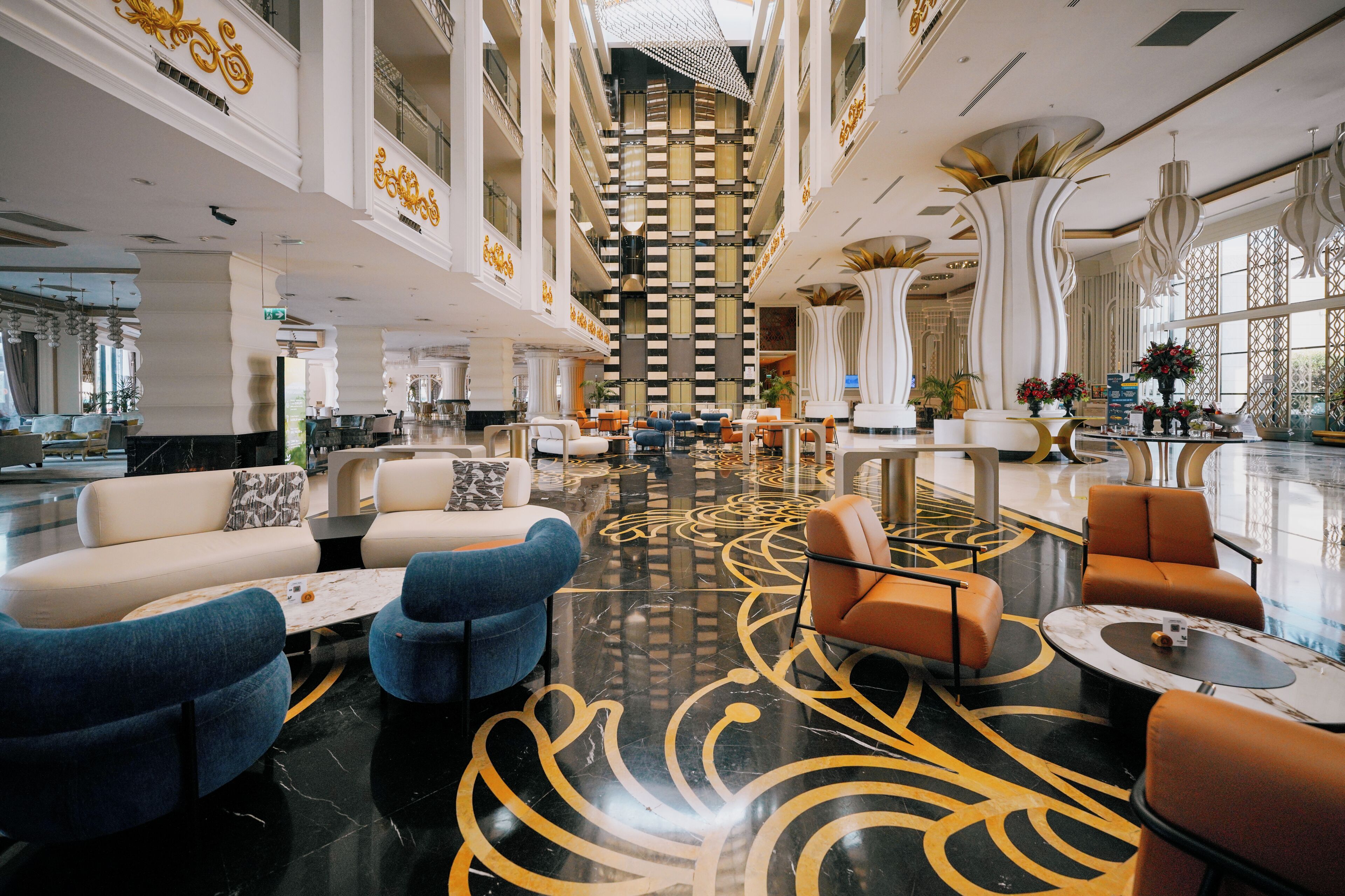 A spacious lobby with a high ceiling, modern seating arrangements, and a decorative floor pattern.