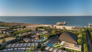 A resort with a large pool area, a water slide, and a beach with umbrellas. - Adalya Elite Lara Hotel - All Inclusive (Antalya)