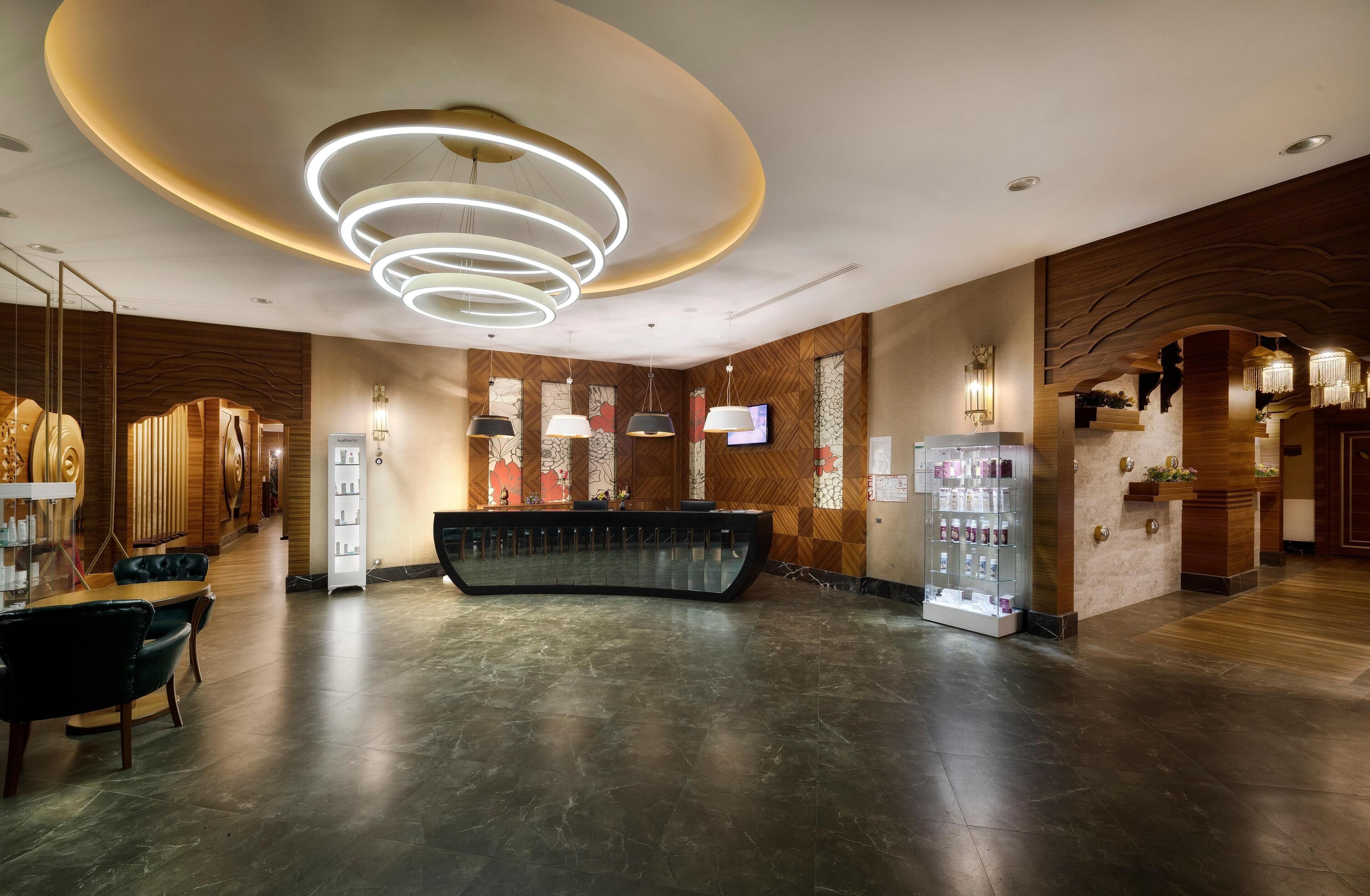 A modern hotel lobby with a curved reception desk, contemporary lighting fixtures, and a wooden wall design.