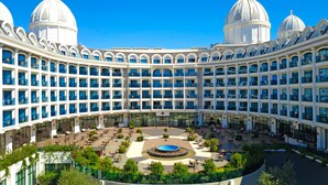 A large hotel with a central courtyard, multiple balconies, and a dome-shaped roof. - Adalya Elite Lara Hotel - All Inclusive (Antalya)