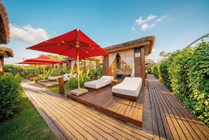 A wooden deck with sun loungers and red umbrellas, surrounded by lush greenery. - Adalya Elite Lara Hotel - All Inclusive (Antalya)