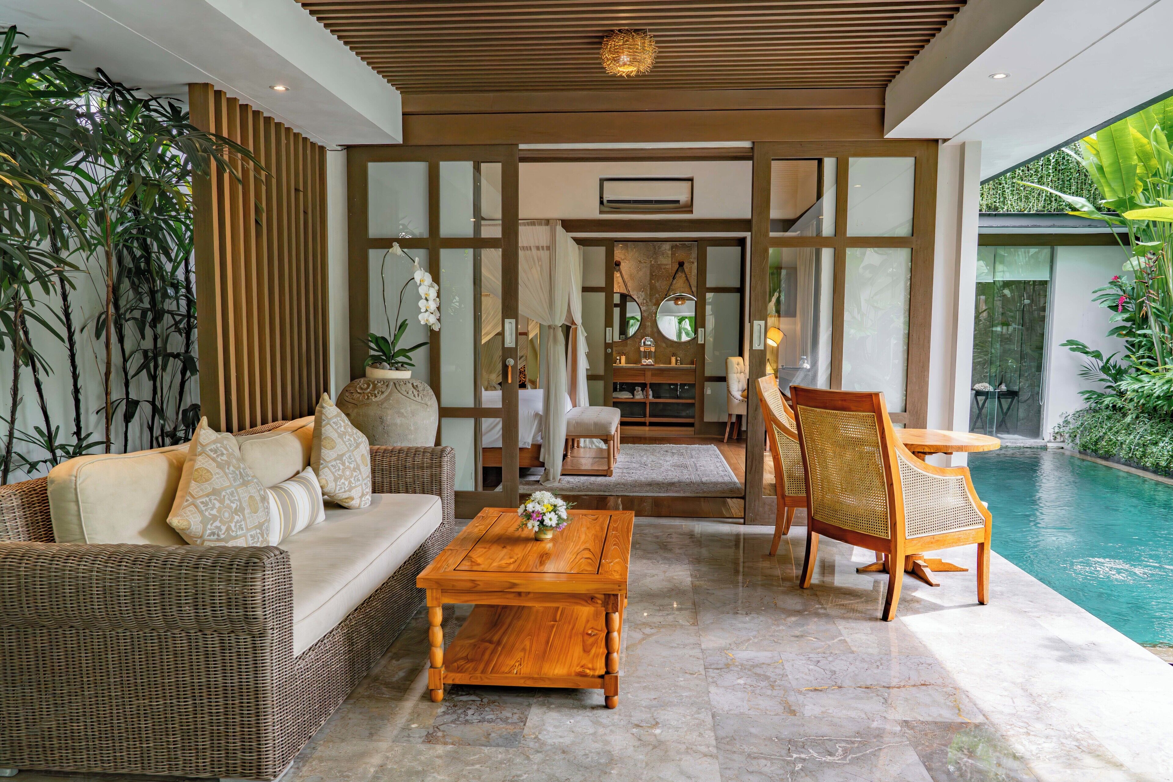 A modern interior with a pool, wicker furniture, and a wooden coffee table.
