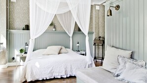 A bedroom with a double bed, a bedside table, a lamp, and a nightstand. - Okens Bed & Breakfast (Varberg)