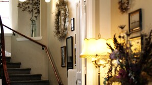 A staircase with a wooden handrail leading to a landing. A chair and a table with a lamp are positioned on the landing. - Okens Bed & Breakfast (Varberg)
