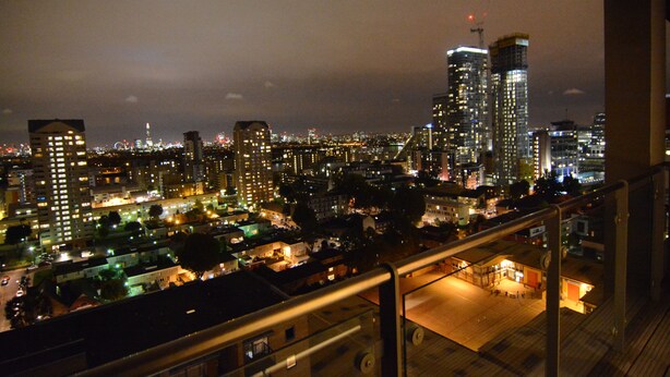 A nighttime cityscape with illuminated buildings and a view of a city from a high vantage point. - Apartment Wharf - Indescon Wharf (London)