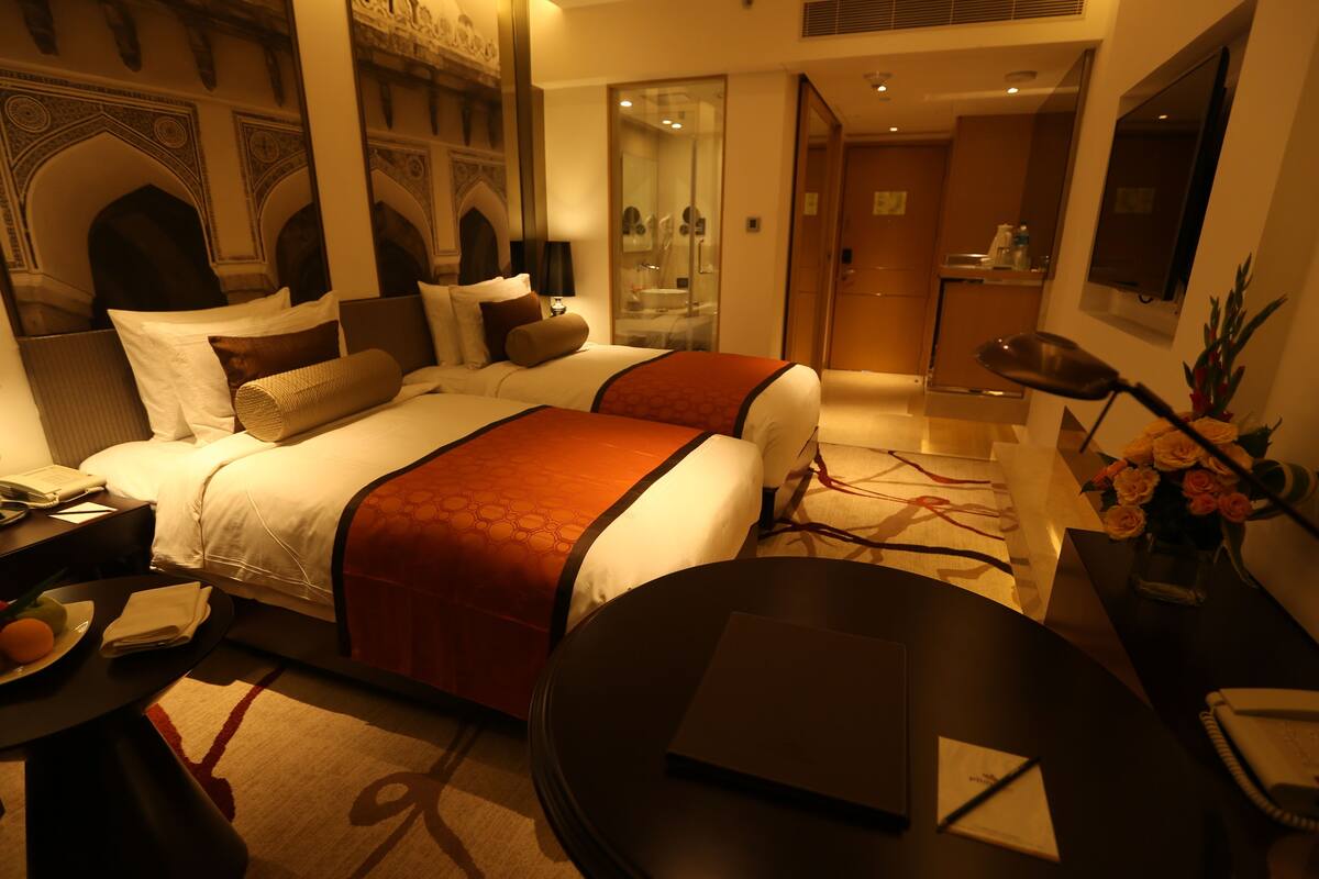 A hotel room with a large bed, a desk, a chair, and a bathroom visible through an open door.
