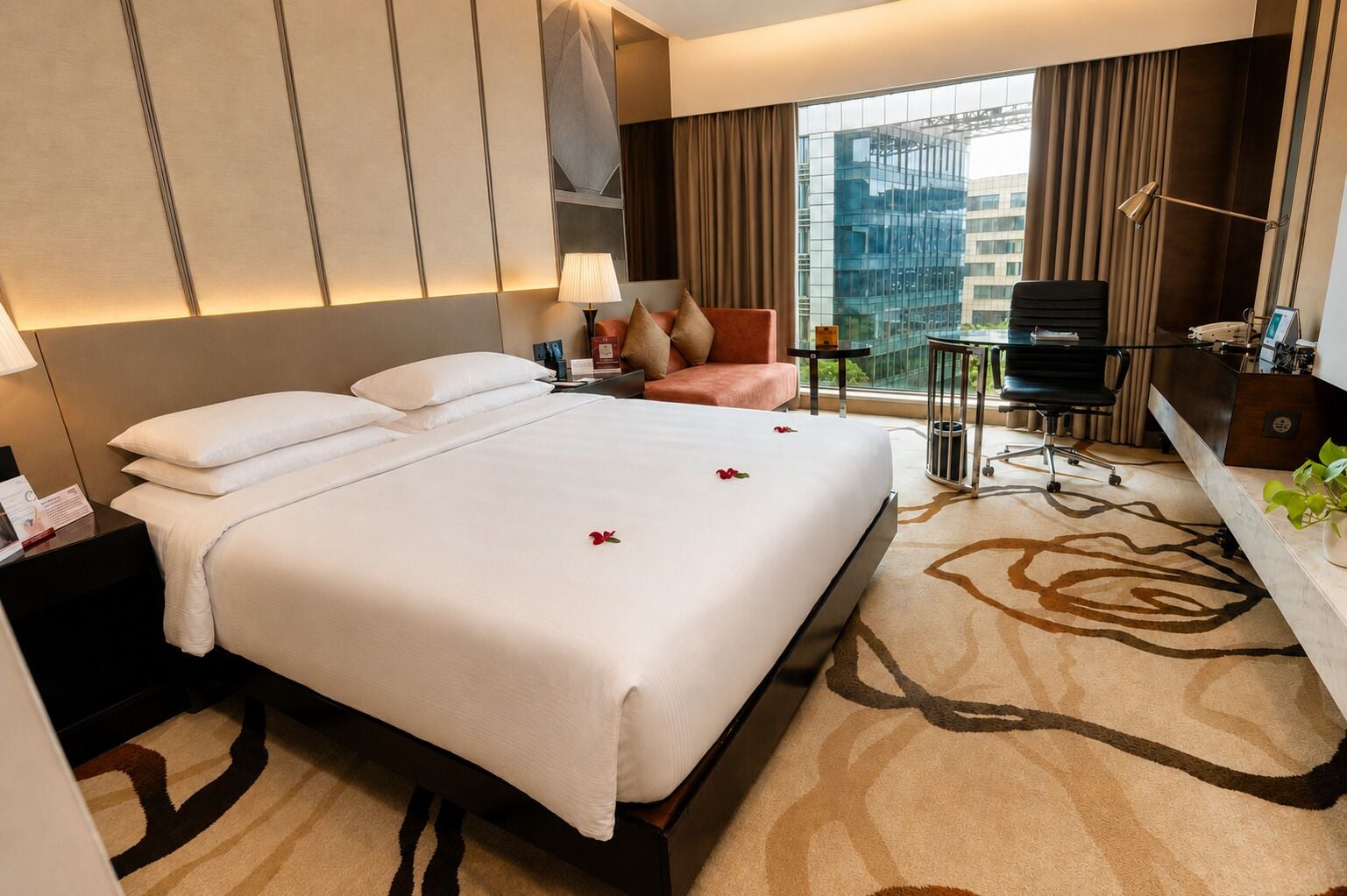 Habitación de hotel con una cama grande, un escritorio, una silla, una lámpara de escritorio y vistas a la ciudad.