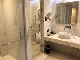 A modern bathroom with a glass shower enclosure, a marble sink, and a large mirror.
