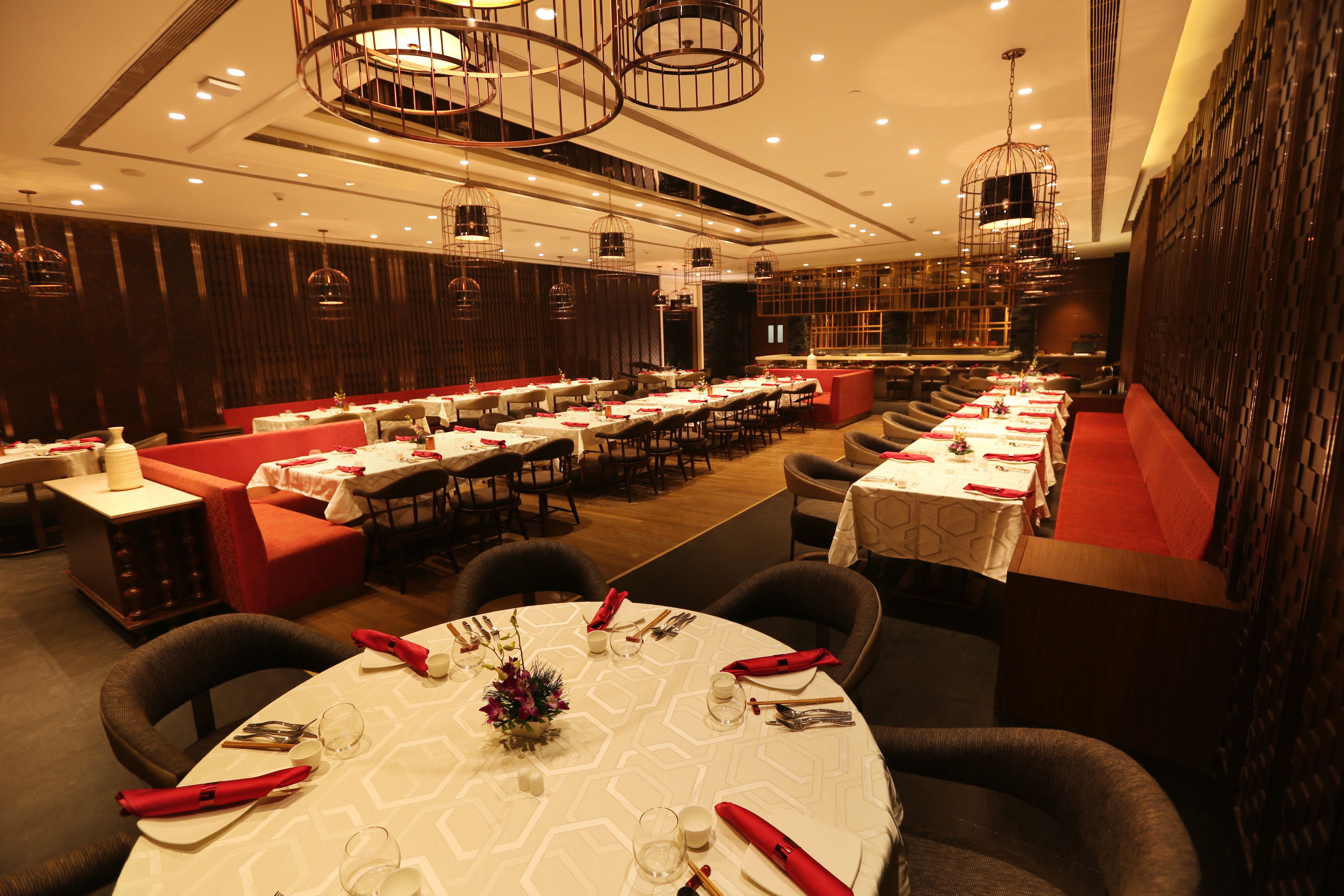 A restaurant with round tables, red upholstered booths, and a modern interior design.