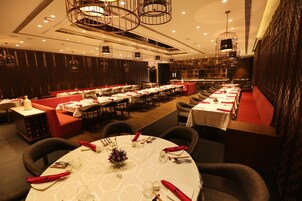Un restaurante con mesas redondas, cabinas tapizadas en rojo y una decoración de diseño moderno.