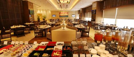 Un comedor de hotel con varias mesas y un bufé con diferentes opciones de comida.