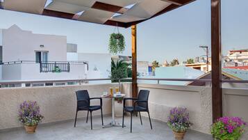Una terraza en la azotea con una mesa y sillas, plantas en macetas y vistas de la ciudad.