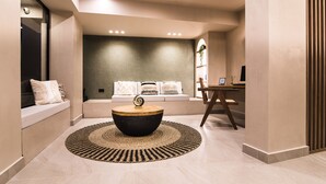 A modern interior with a round coffee table, a sofa with cushions, and a wall-mounted shelf with a plant. - Le Palme (Hersonissos)