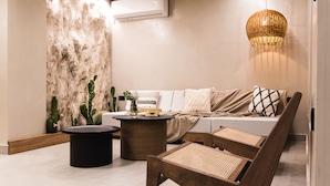 A modern living room with a sofa, a round coffee table, and a wicker lamp. - Le Palme (Hersonissos)