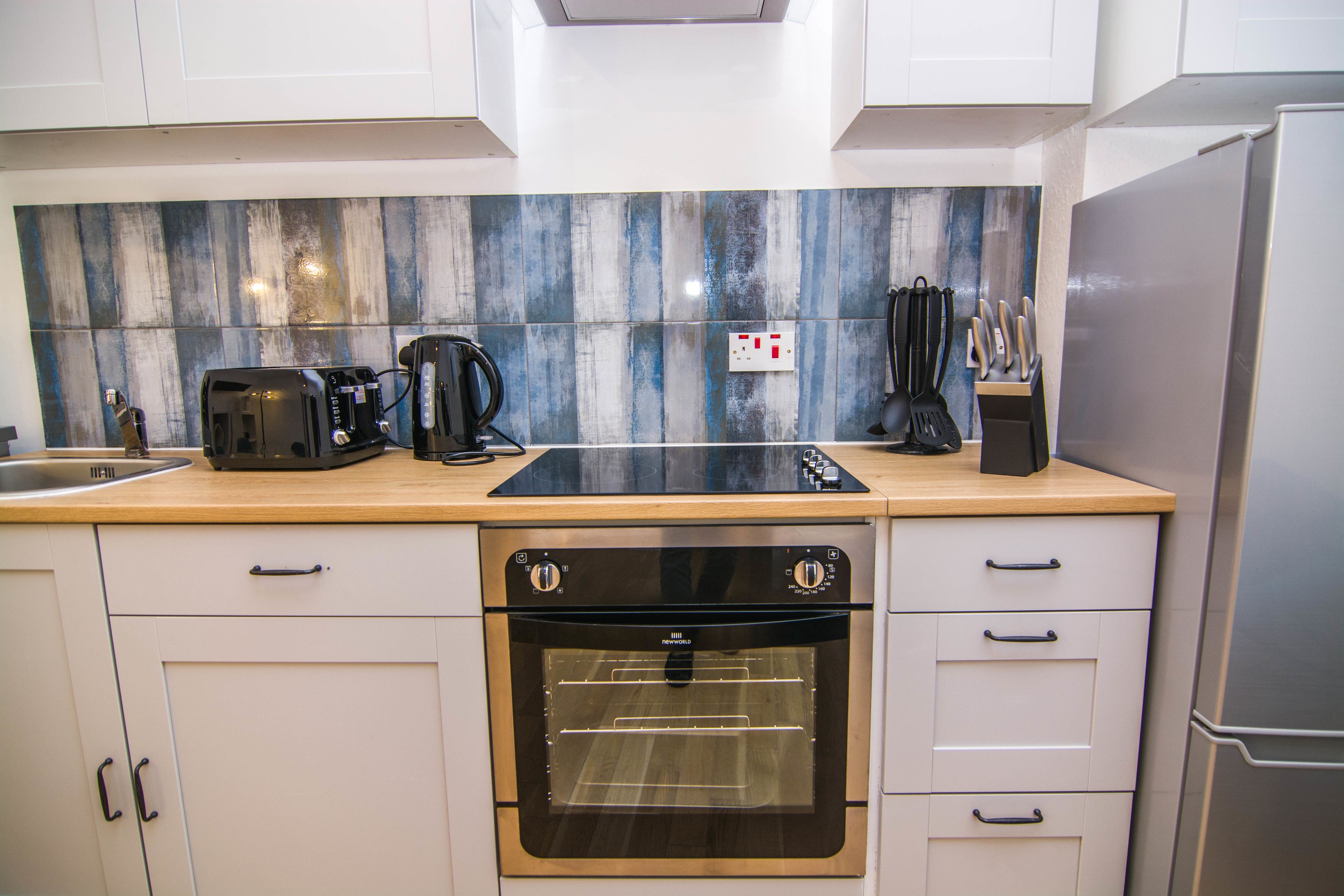 A modern kitchen with white cabinets, a built-in oven, a coffee maker, and a toaster.