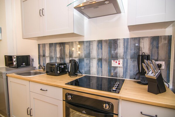 A modern kitchen with a stainless steel oven, a built-in microwave, a toaster, and a coffee maker.