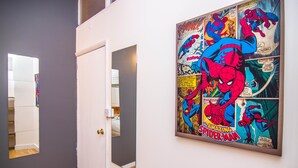 Ein Flur mit einer Tür zu einem Schlafzimmer, einem Spiegel an der Wand und einem Spiderman-Comic an der Nachbarwand.