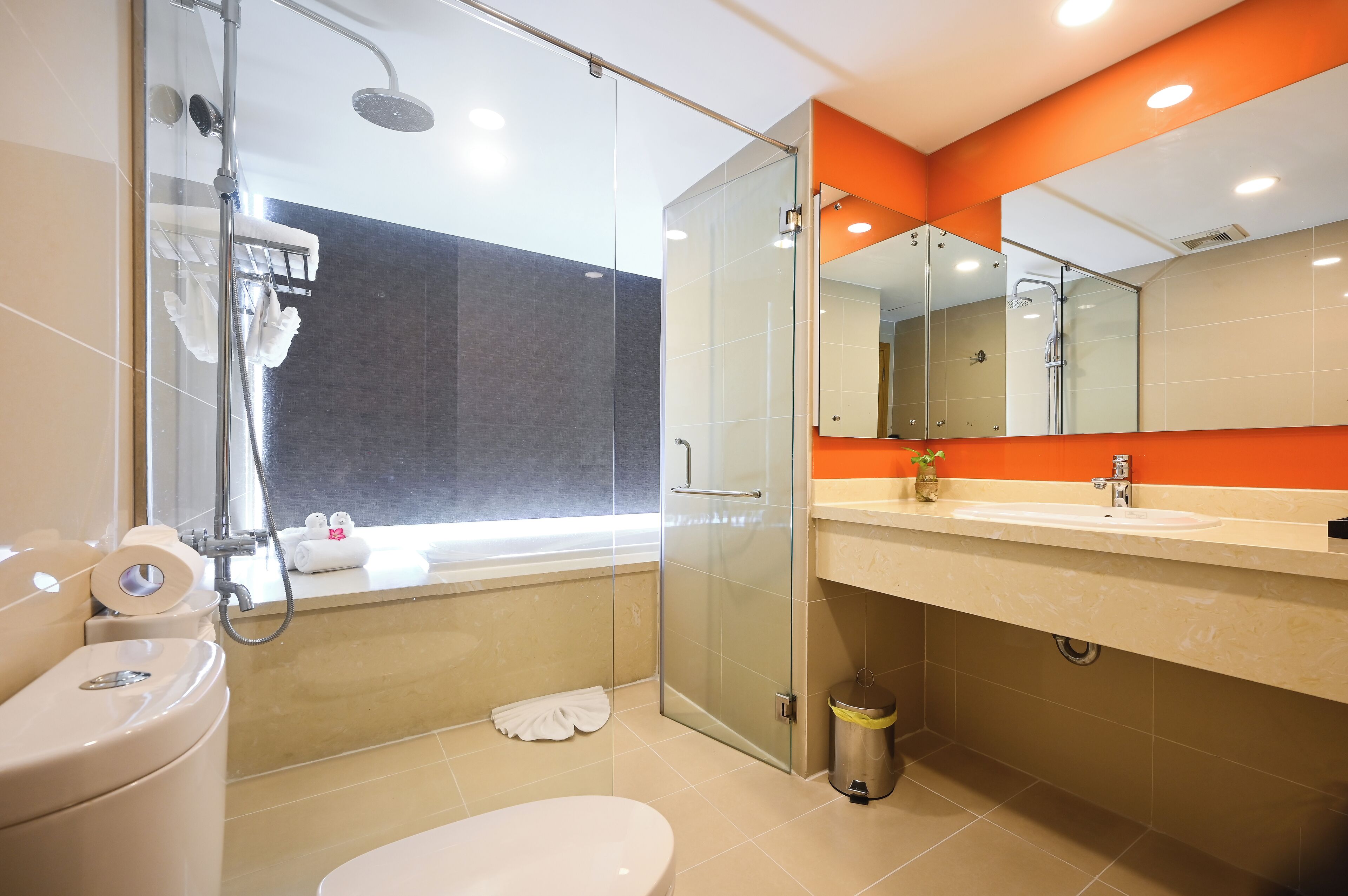 Un bagno moderno con cabina doccia in vetro, un water, un lavandino e uno specchio.