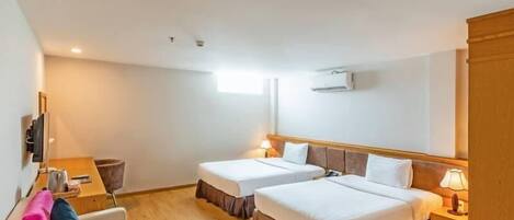 Une chambre d’hôtel avec deux lits, un canapé, une télévision et un plancher en bois.