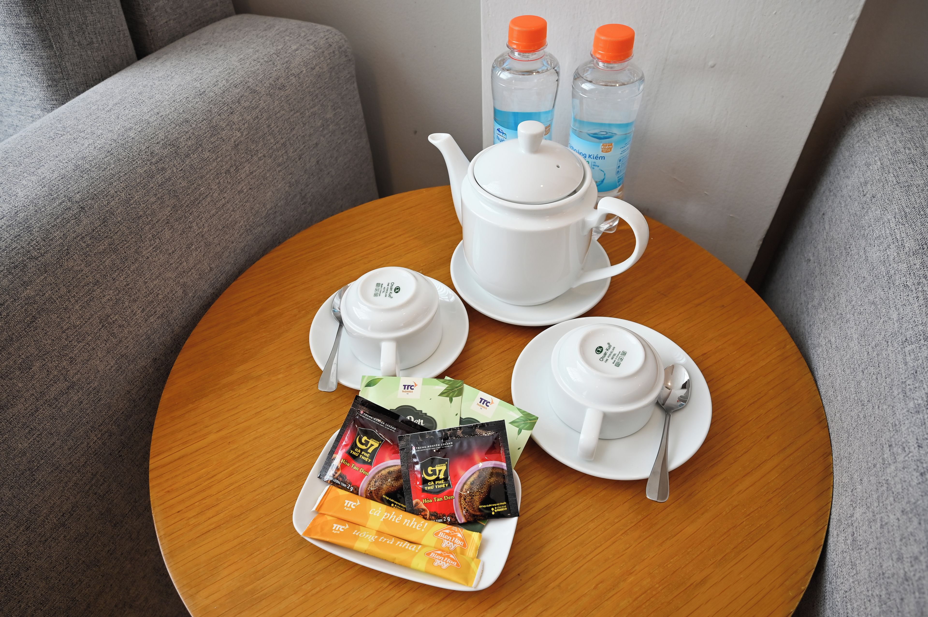 A table with a teapot, two cups, a spoon, and tea packets.