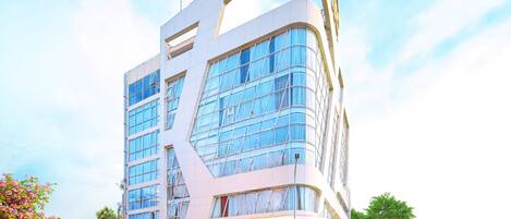 Un edificio moderno con fachada curva, ventanas amplias y un llamativo letrero amarillo en la parte superior.
