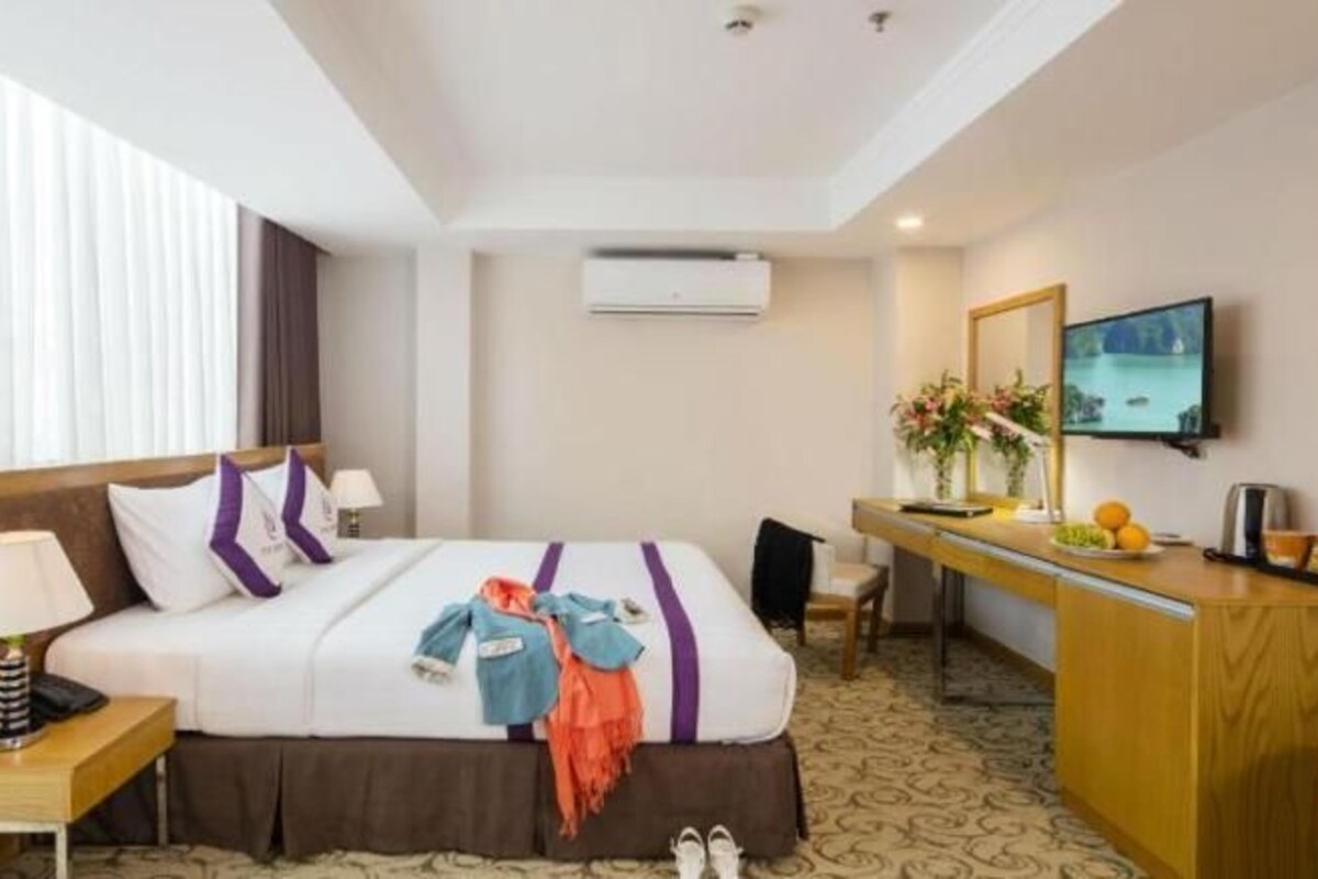 Ein Hotelzimmer mit Bett, Nachttisch, Schreibtisch und Fernseher.