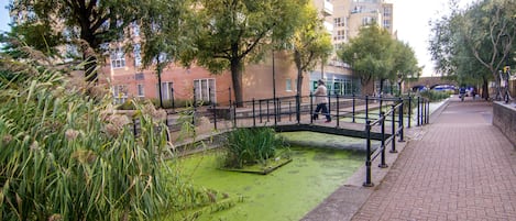 A pedestrian bridge over a water feature with a brick pathway on the right.