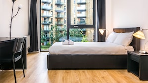 A modern hotel room with a large bed, a desk, and a chair.
