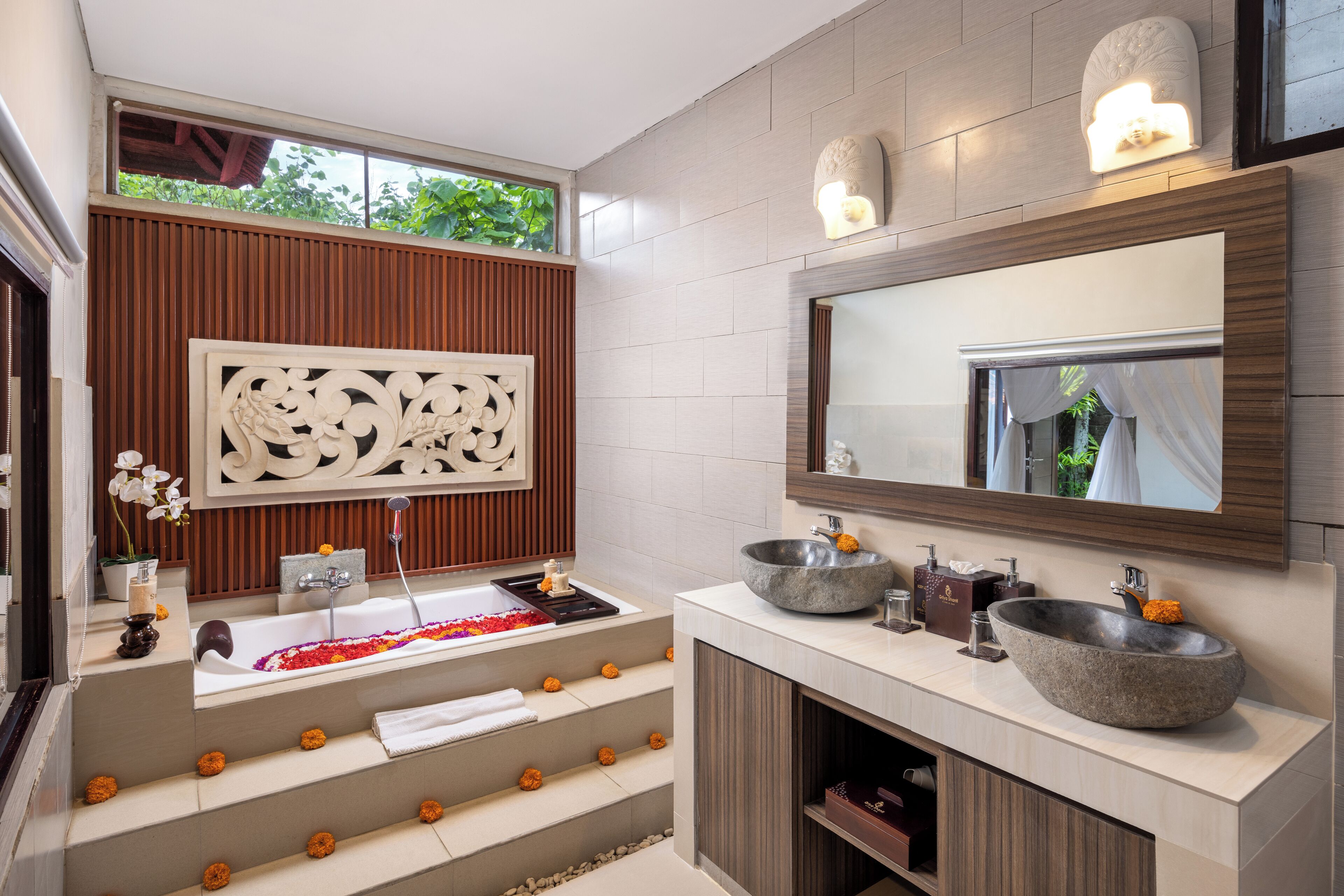 A modern bathroom with a freestanding bathtub, a large mirror, and a vanity with two bowls.
