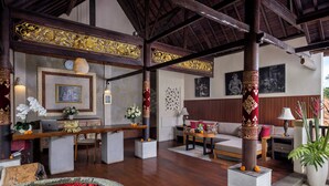 Een ruime lobby met een houten plafond, een receptiebalie, een zithoek met een bank en stoelen, en een decoratieve pilaar.