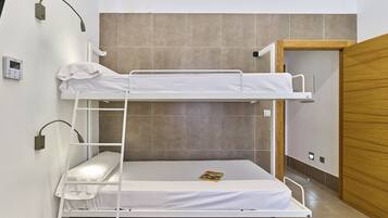 Een slaapkamer met een stapelbed, een tafeltje en een deur.