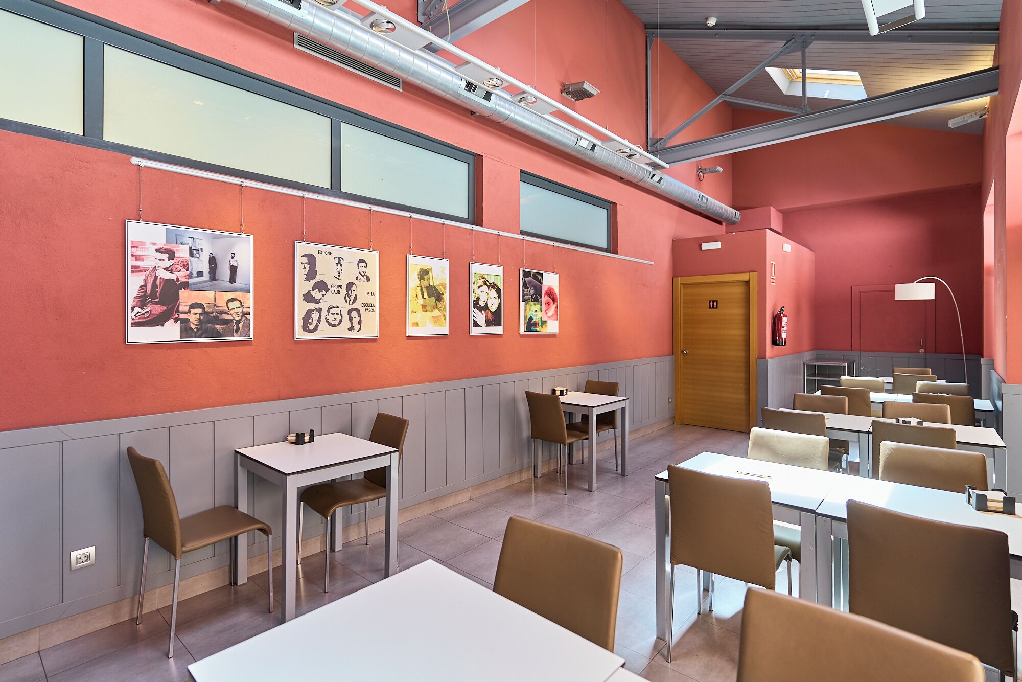A restaurant with tables and chairs, a fire extinguisher, and artwork on the walls.