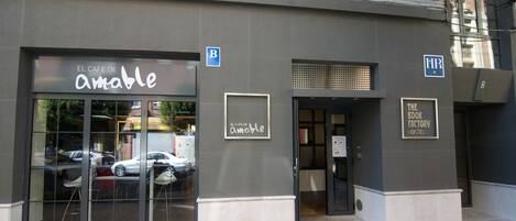 Un edificio con una cafetería llamada 'El Cafe De Amable' y un albergue llamado 'The Book Factory Hostel'.