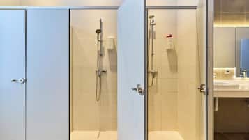 Un baño con dos cabinas de ducha, un lavabo y un espejo.