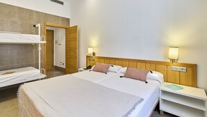 A hotel room with a large bed, a smaller bed, a desk, and a bedside table. - The Book Factory Hostel by gaiarooms (Valladolid)